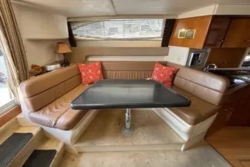 Slide: The Image of 2002 Carver 350 Mariner interior with dining area, brown seating, and red cushions. - 16