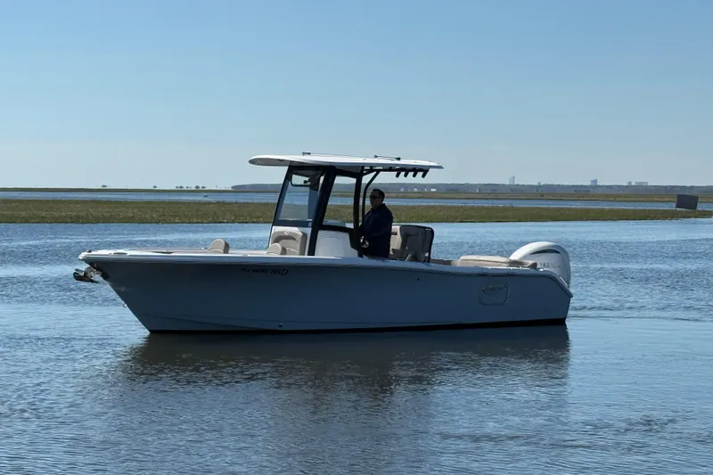 Slide: The Image of 2025 Sea Hunt Ultra 255 SE boat cruising on calm water under clear sky. - 2