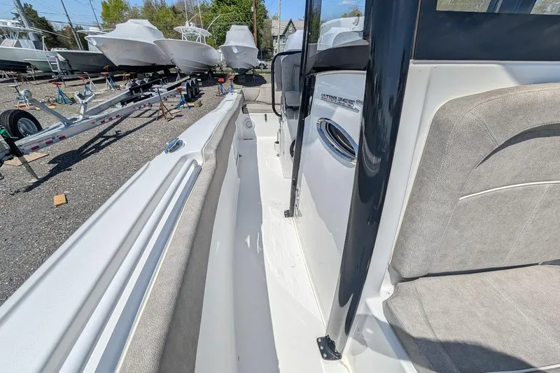 Slide: The Image of 2025 Sea Hunt Ultra 255 SE boat interior with seating and storage, parked outdoors. - 23