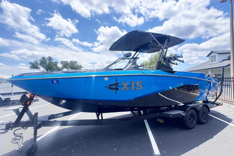 The Image of 2025 Axis A245 boat in vibrant blue on a trailer under a partly cloudy sky. - 1