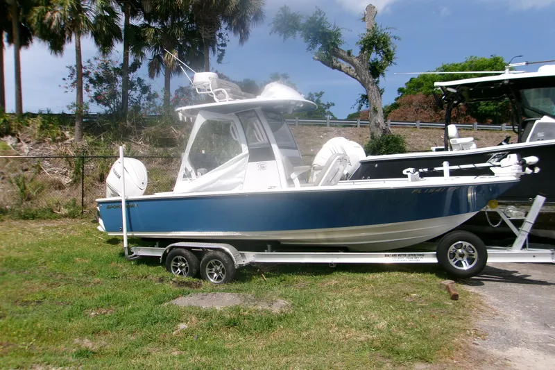 The Image of 2025 Sportsman Masters 247OE Bay Boat on trailer, parked outdoors near trees. - 1