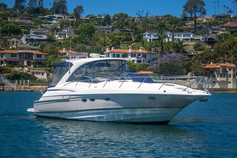 Slide: The Image of 2003 Regal Commodore 4260 yacht cruising near scenic coastal homes. - 4