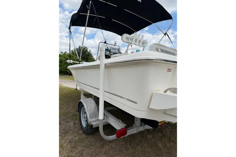 Slide: The Image of 2016 Bulls Bay 2000 boat on trailer with canopy, parked on grass under cloudy sky. - 11