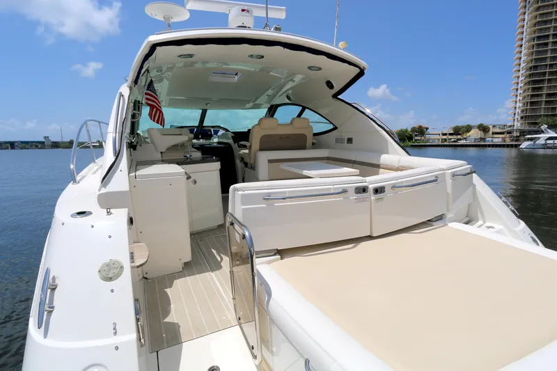 Slide: The Image of 2013 Searay 41 yacht with spacious deck, docked by waterfront under clear blue sky. - 2