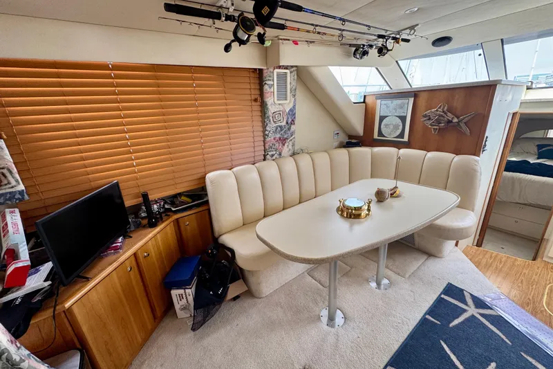 Slide: The Image of 1999 Silverton 351 Sedan interior with dining area, fishing rods, and cozy seating. - 13
