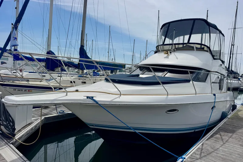 Slide: The Image of 1999 Silverton 351 Sedan yacht docked at marina with sailboats in background. - 2