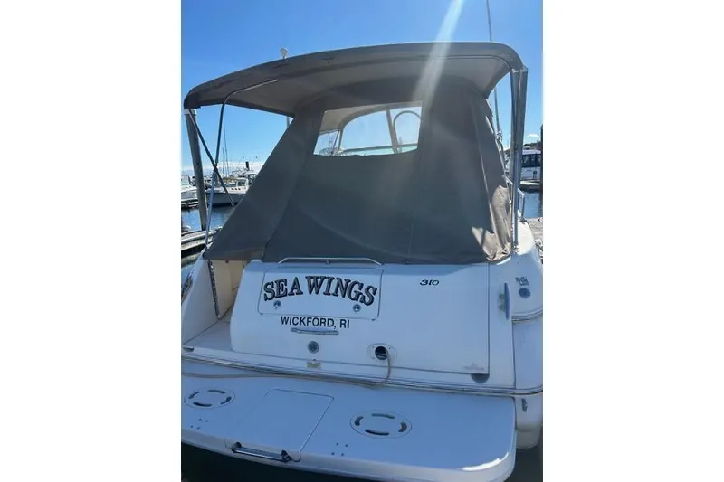 Slide: The Image of 2002 Sea Ray Sundancer 310 boat docked, rear view with canopy and "Sea Wings" name. - 10
