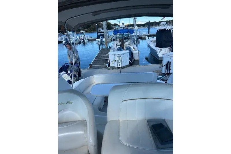 Slide: The Image of 2002 Sea Ray Sundancer 310 interior at marina, showcasing seating and docked boats. - 19