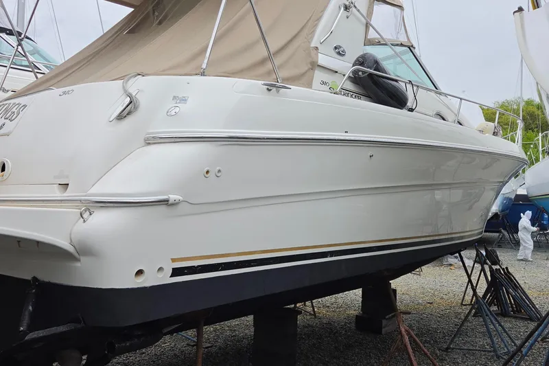 Slide: The Image of 2002 Sea Ray Sundancer 310 yacht on dry dock, side view with beige canopy. - 2