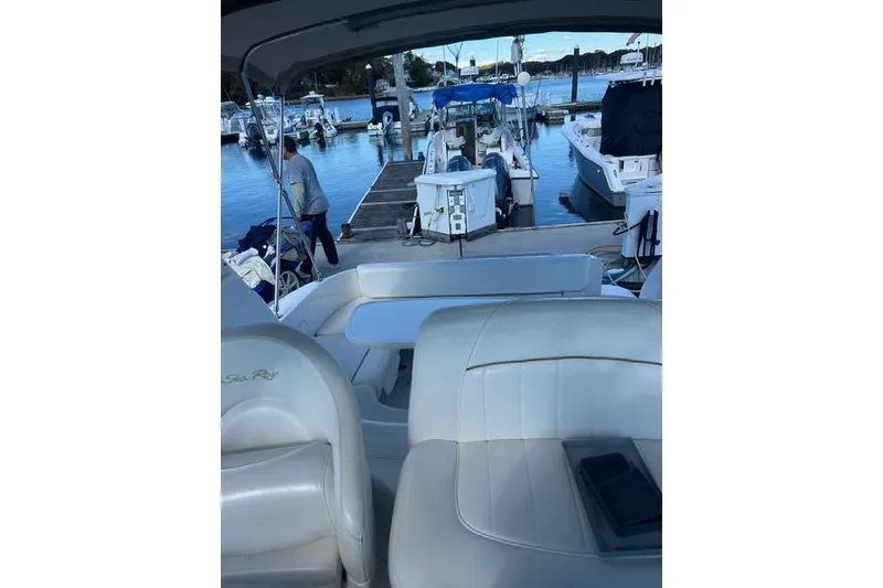 Slide: The Image of 2002 Sea Ray Sundancer 310 at marina, featuring white leather seating and docked boats. - 20