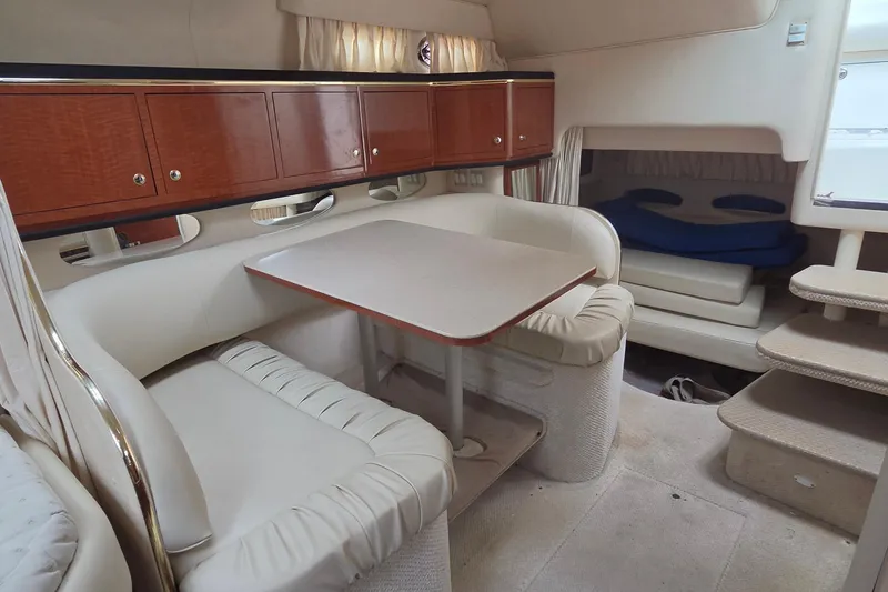 Slide: The Image of 2002 Sea Ray Sundancer 310 interior with cozy seating, table, and wooden cabinets. - 30