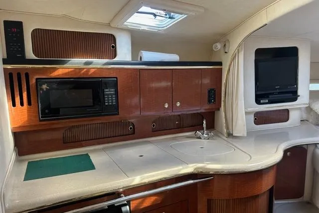 Slide: The Image of 2002 Sea Ray Sundancer 310 interior with kitchenette, microwave, and TV. - 31
