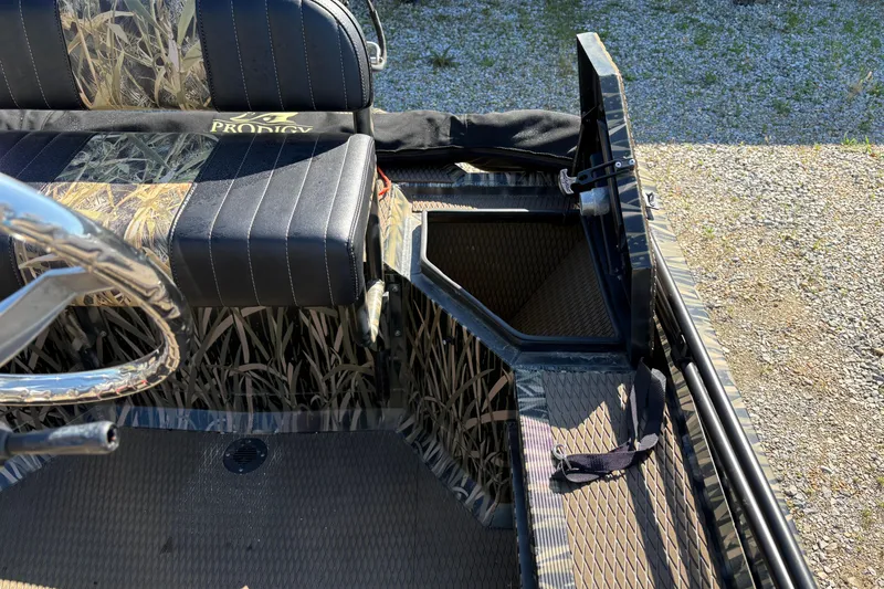 Slide: The Image of 2022 Prodigy 18' PRO VS boat interior with camo seats and open storage compartment. - 13