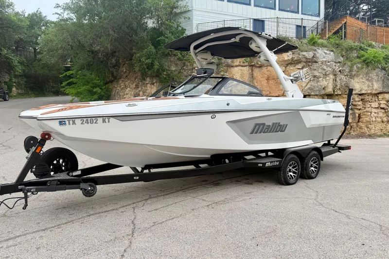Slide: The Image of 2023 Malibu Wakesetter 24 MXZ boat on trailer, parked outdoors near rocky terrain. - 13