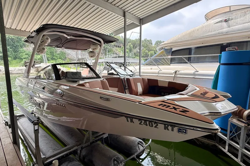 Slide: The Image of 2023 Malibu Wakesetter 24 MXZ boat docked under a covered marina. - 16
