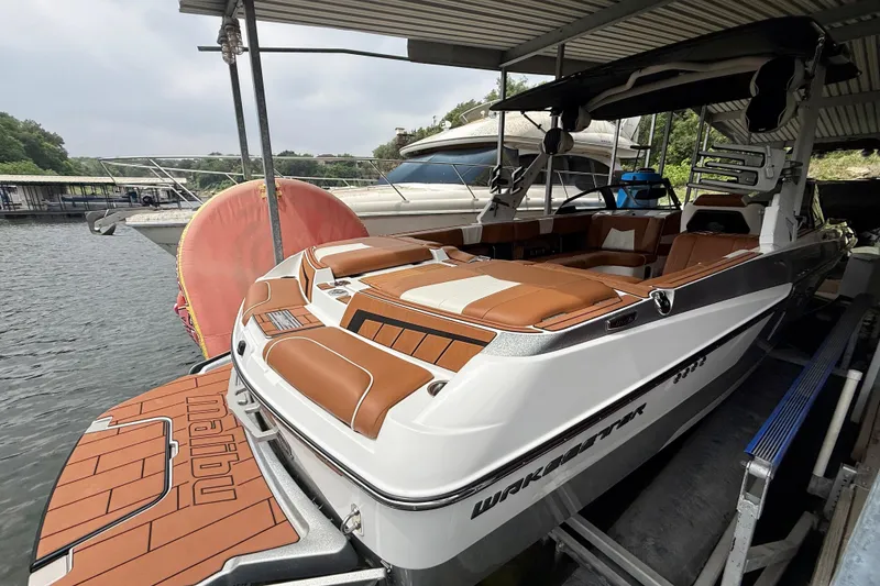 Slide: The Image of 2023 Malibu Wakesetter 24 MXZ boat docked, featuring sleek design and luxurious seating. - 17