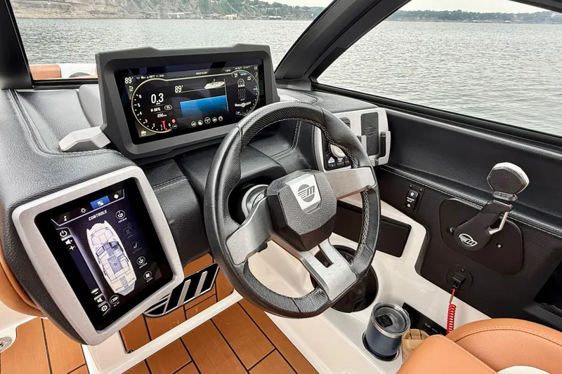 Slide: The Image of 2023 Malibu Wakesetter 24 MXZ dashboard with advanced controls and steering wheel on a lake. - 25