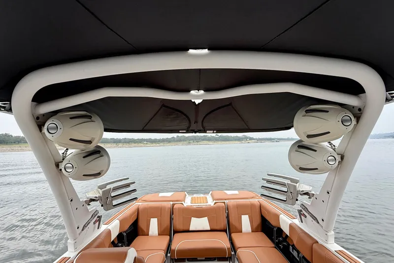 Slide: The Image of 2023 Malibu Wakesetter 24 MXZ interior with speakers and seating on a lake. - 29