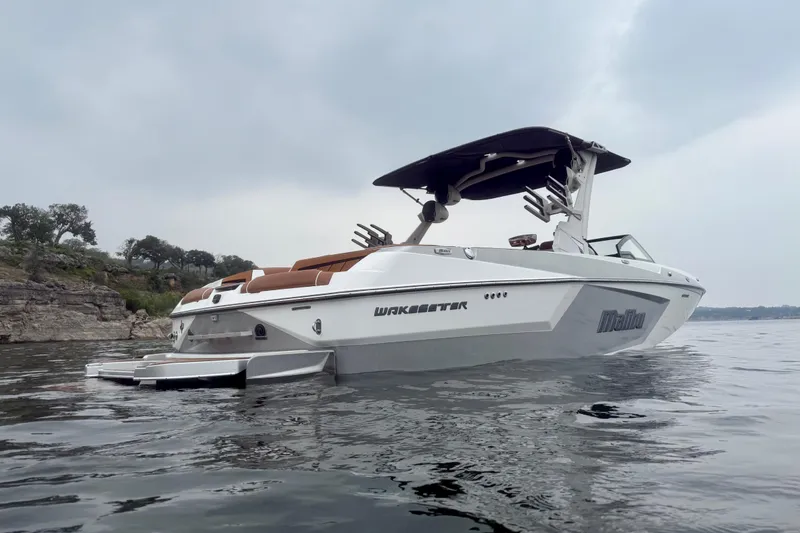 Slide: The Image of 2023 Malibu Wakesetter 24 MXZ boat on calm water, overcast sky. - 3