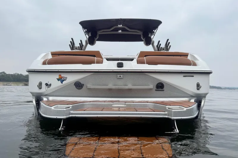 Slide: The Image of 2023 Malibu Wakesetter 24 MXZ boat on water, rear view with sleek design. - 4