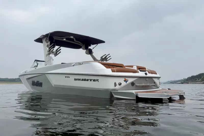 Slide: The Image of 2023 Malibu Wakesetter 24 MXZ boat on calm water, showcasing sleek design and luxury features. - 5