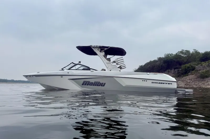 Slide: The Image of 2023 Malibu Wakesetter 24 MXZ boat on calm water, overcast sky. - 6