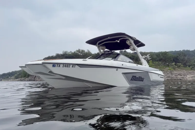 Slide: The Image of 2023 Malibu Wakesetter 24 MXZ boat on calm water, scenic background. - 7