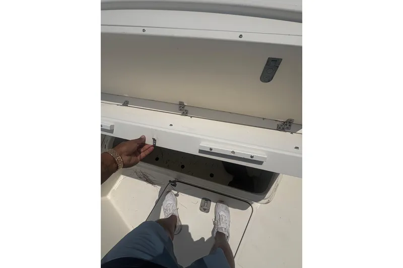 Slide: The Image of Person opening storage compartment on 1998 Pursuit 2870 Center Console boat. - 22
