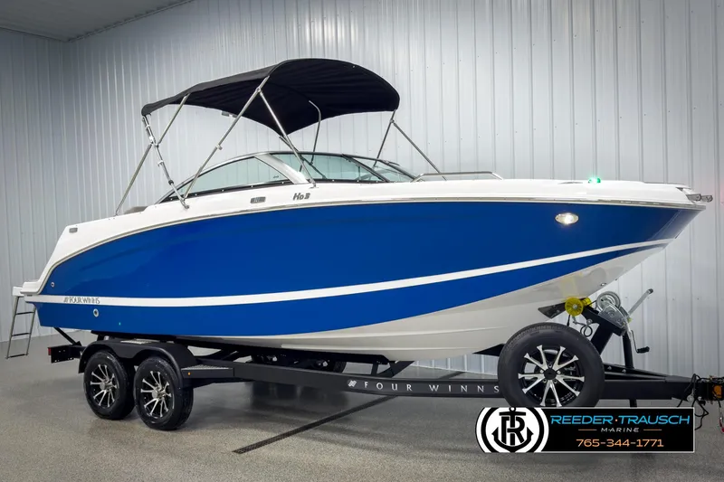 Slide: The Image of 2025 Four Winns HD3 boat with blue hull on trailer in showroom. - 3