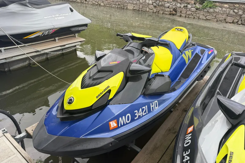 Slide: The Image of 2020 Sea-Doo Wake 170 jet ski in vibrant blue and yellow, docked by the water. - 2