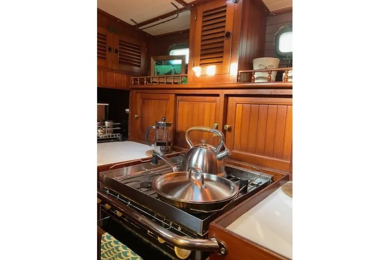 Slide: The Image of Vintage 1983 Vagabond 42 yacht kitchen with wooden cabinetry and stainless steel cookware. - 9