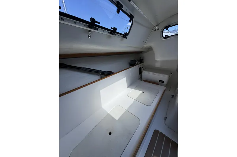 Slide: The Image of Interior view of a 2011 J Boats J/95 sailboat, featuring sleek white surfaces and storage compartments. - 26