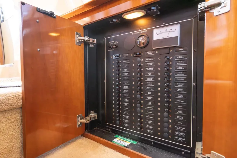 Slide: The Image of Electrical control panel inside 2003 Carver 530 Voyager Pilothouse yacht, with open wooden cabinet door. - 70