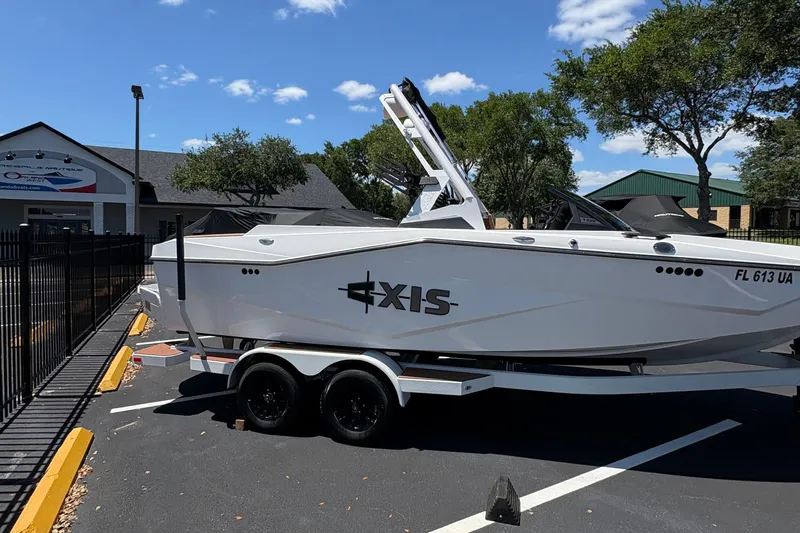 Slide: The Image of 2025 Axis T220 boat on trailer in parking lot, sunny day, dealership in background. - 3