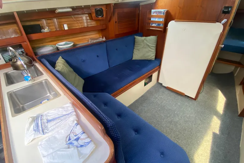 Slide: The Image of Interior of a 1987 Catalina 30 MkII sailboat with blue seating and kitchenette. - 24