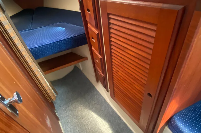Slide: The Image of Interior of 1987 Catalina 30 MkII sailboat with wooden cabinetry and blue cushioned berth. - 27
