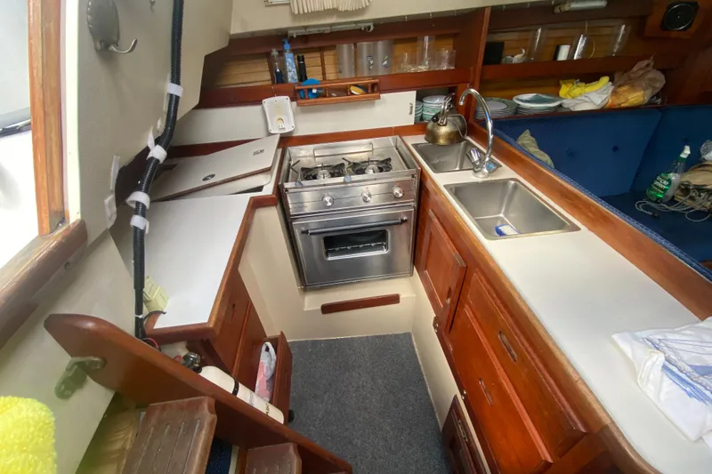 Slide: The Image of Interior of 1987 Catalina 30 MkII sailboat kitchen with stove, sink, and wooden cabinetry. - 29