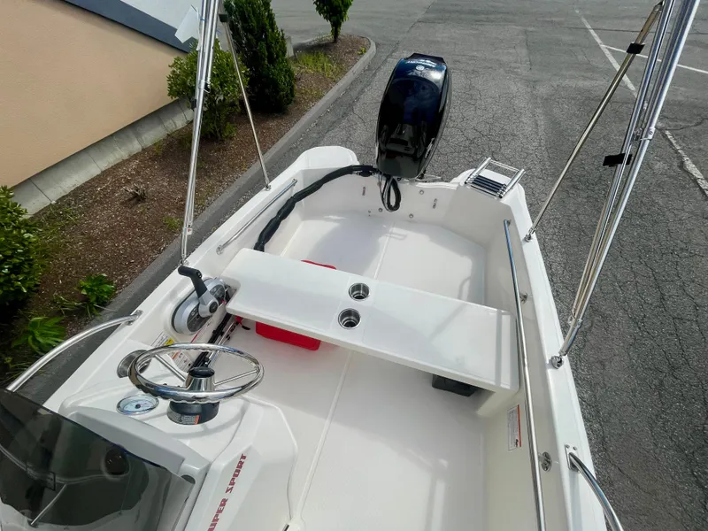 Slide: The Image of The image shows a 2027 Boston Whaler 130 Super Sport boat. It features a simple, white deck with a helm and outboard motor. - 7