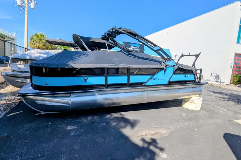 The Image of 2026 Trifecta 23SB2 SS pontoon boat with blue and black design, covered and docked outdoors. - 0