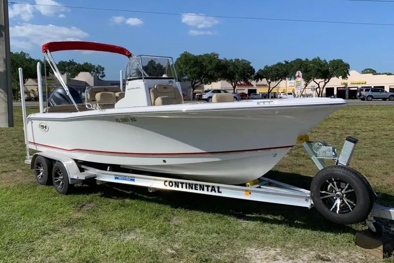 Slide: The Image of 2018 Sea Hunt Ultra 211 boat on trailer, parked on grass under clear sky. - 2