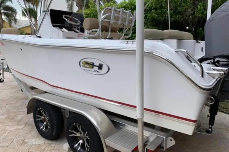 Slide: The Image of 2018 Sea Hunt Ultra 211 boat on trailer, white with red trim, parked outdoors. - 3