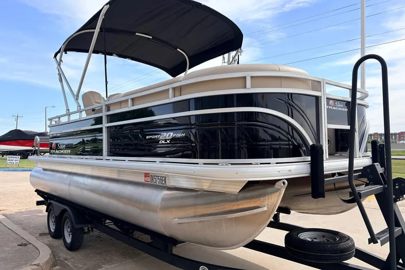 Slide: The Image of 2025 Sun Tracker SportFish 20 DLX pontoon boat on trailer, black exterior, sunny day. - 5