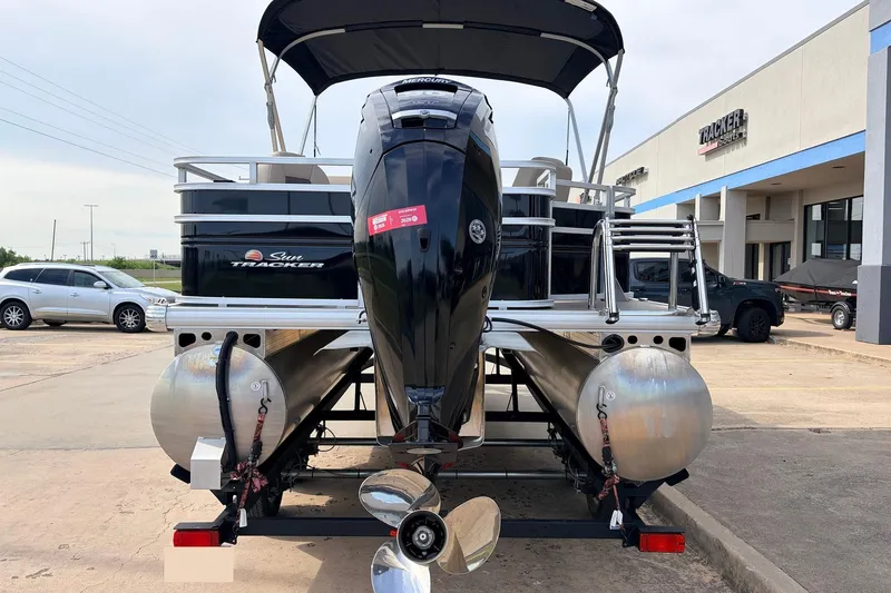 Slide: The Image of 2025 Sun Tracker SportFish 20 DLX pontoon boat with outboard motor, parked at dealership. - 8