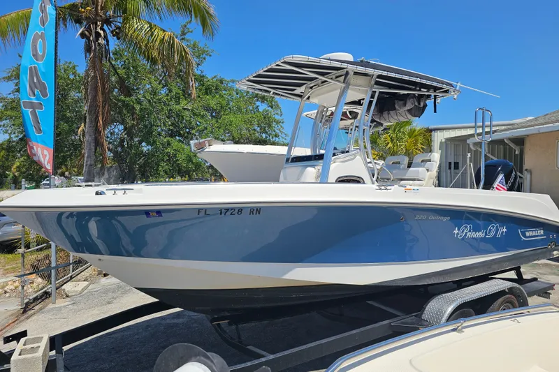 Slide: The Image of 2012 Boston Whaler 220 Outrage boat on trailer, blue hull, sunny day. - 4