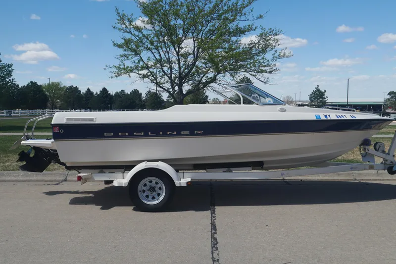 The Image of 2003 Bayliner 194 boat on trailer, parked outdoors under a clear blue sky. - 11