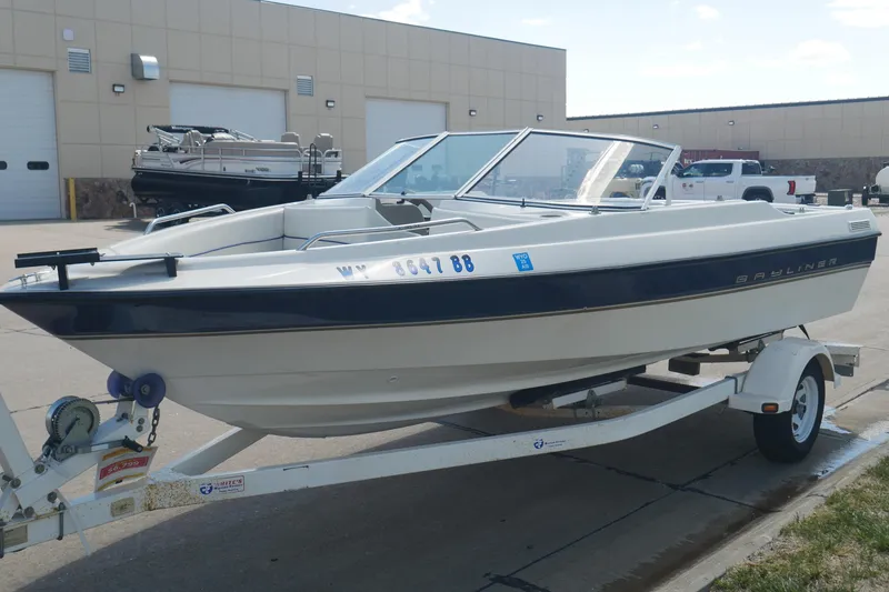 Slide: The Image of 2003 Bayliner 194 boat on trailer, parked outside a warehouse. - 13