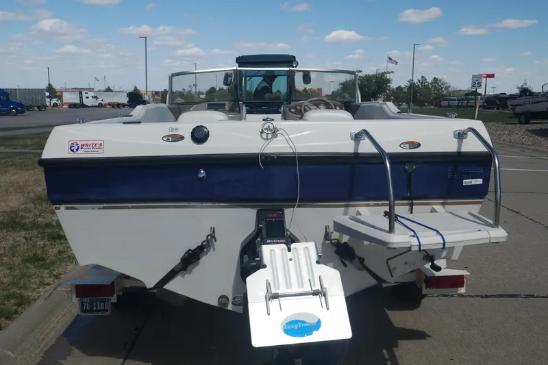 Slide: The Image of 2003 Bayliner 194 boat with blue and white exterior, parked on a trailer in a lot. - 14