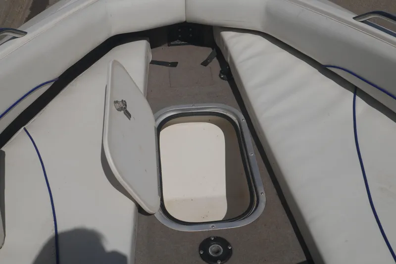 Slide: The Image of 2003 Bayliner 194 boat interior with open storage compartment and white seating. - 18