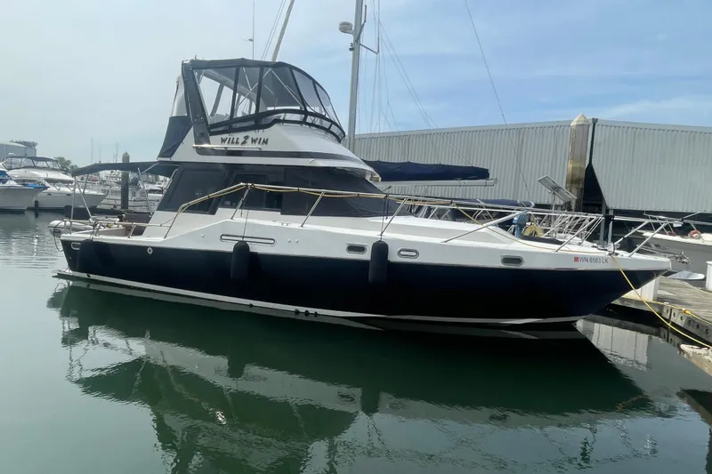 The Image of 1986 Hi-Star 40 Flybridge yacht docked at marina, reflecting on calm water. - 0