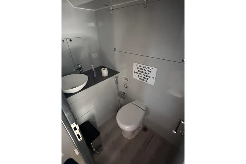 Slide: The Image of Compact bathroom in a 2017 Custom Express cruiser crossover, featuring modern fixtures and a caution sign. - 20
